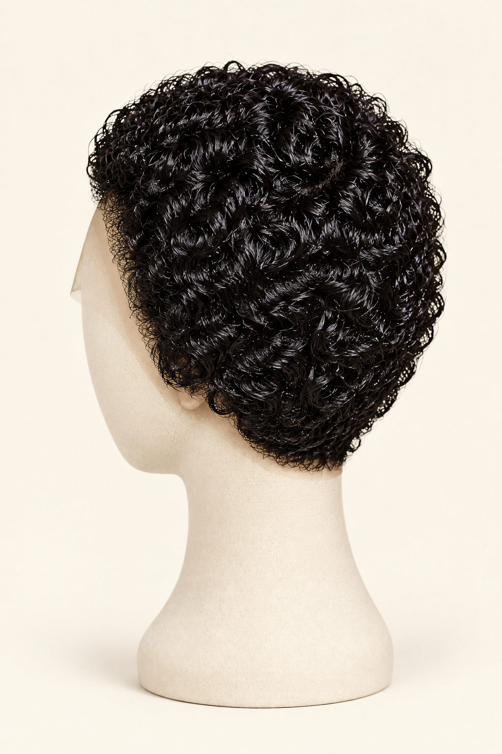 Short, curly black wig displayed on a cream mannequin head from the side against a light beige background.