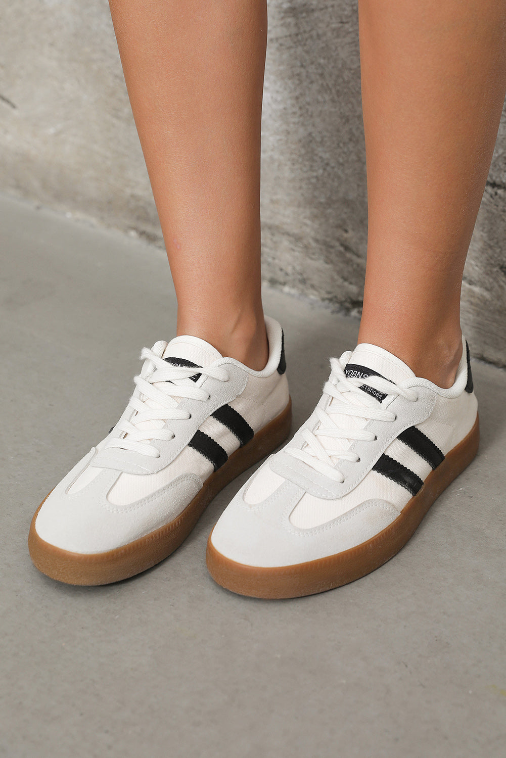 White sneakers with black stripes on a neutral background