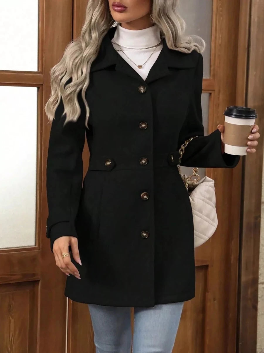 Woman wearing a black coat holding a coffee cup in front of a wooden door.