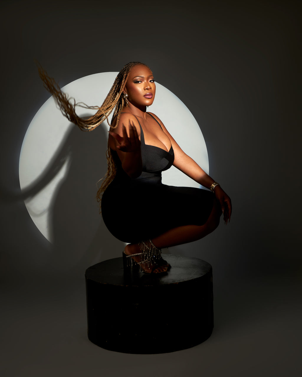 A woman in a mini bodycon bandage dress with a curve-hugging fit and luxe stretch, posing against a circular light background.