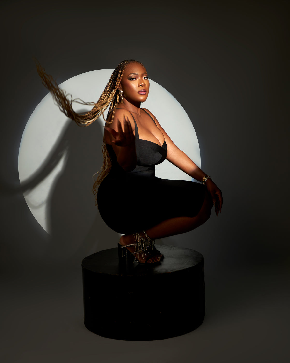 A woman in a mini bodycon bandage dress with a curve-hugging fit and luxe stretch, posing against a circular light background.