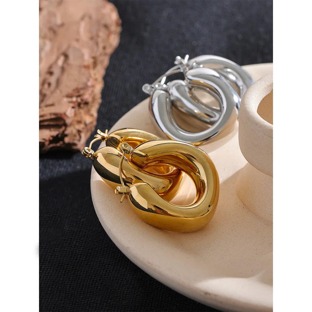 Gold and silver hoop earrings on a marble surface with a dark background