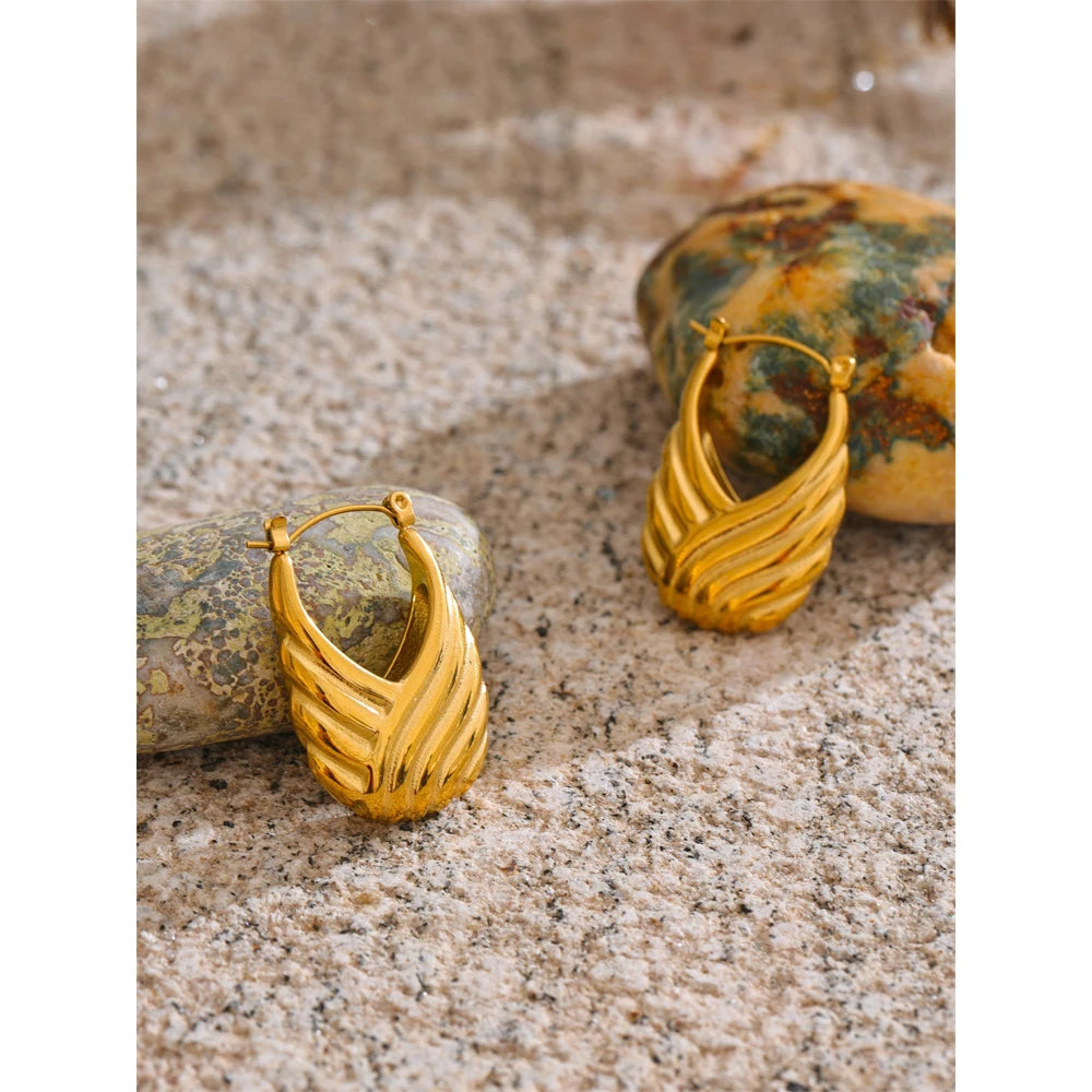 Gold hoop earrings on a textured surface with a natural stone background