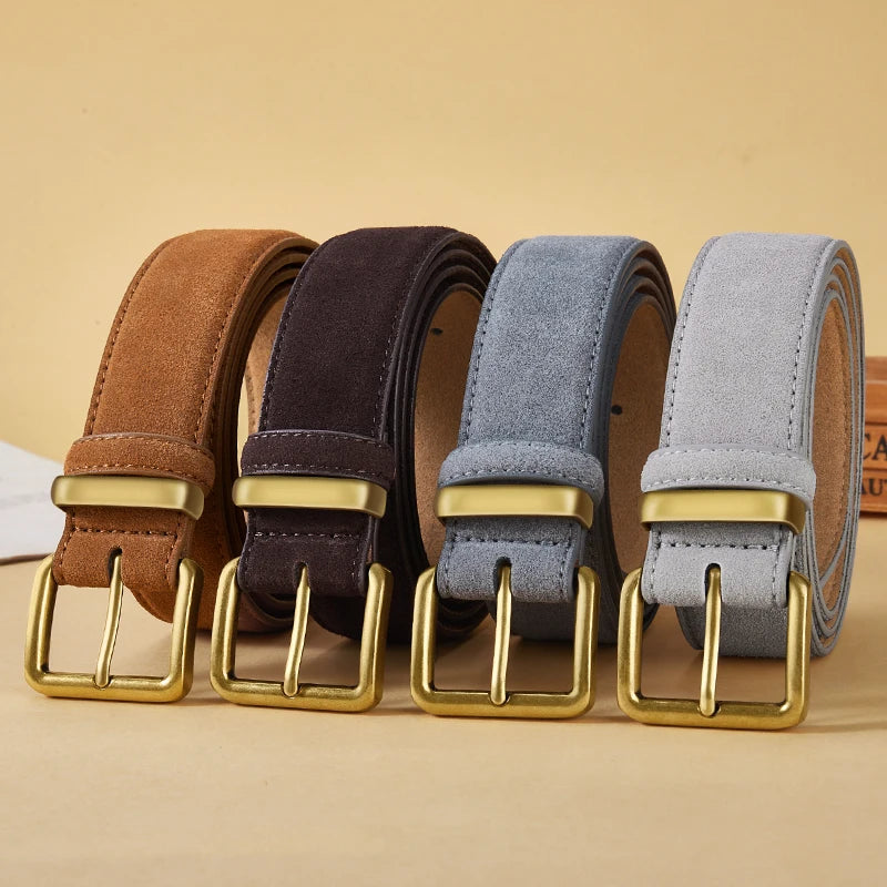 Four suede belts in brown, black, blue, and light gray, each with a gold-tone buckle, arranged side by side on a beige background.