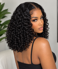 A woman with a three-quarter view showing off a voluminous, short, curly wig. The wig is a deep, rich black with tight, defined curls.