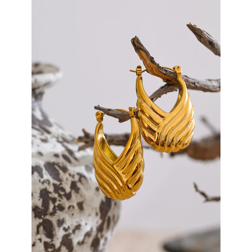 Gold hoop earrings on a branch with a natural background