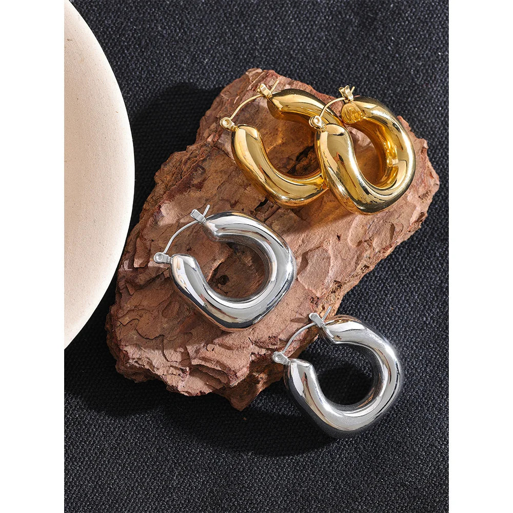 Gold and silver hoop earrings on a textured stone surface