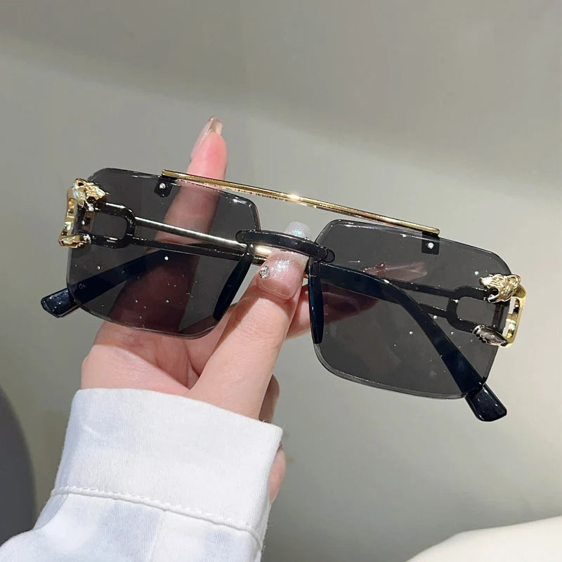 Sunglasses with gold accents held by a hand against a neutral background
