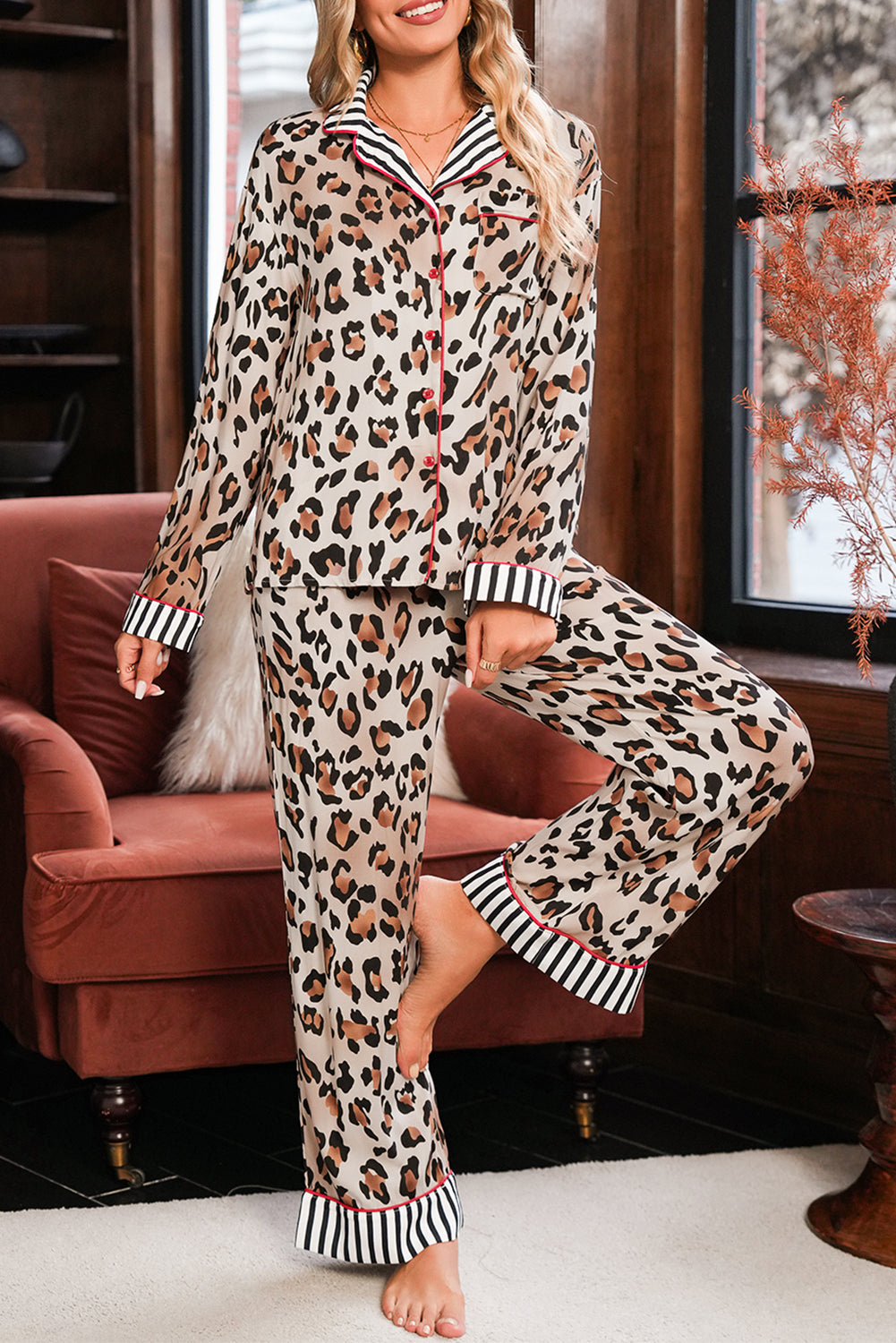 Woman wearing leopard print pajamas sitting on a couch.