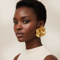 Gold flower stud earrings on a model