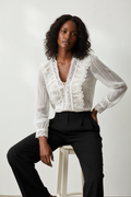 Sheer lace ruffle V-neck blouse styled with tailored trousers