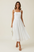 Model wearing a white square-neck midi cami dress with slim straps and a flowing skirt
