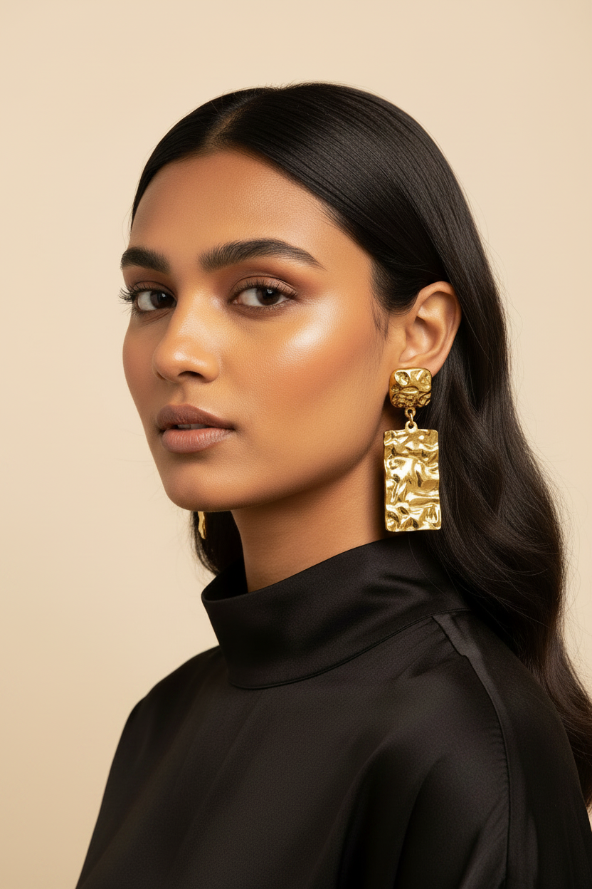 Gold PVD stainless steel rectangle drop earring worn through a pierced earlobe in a close-up portrait