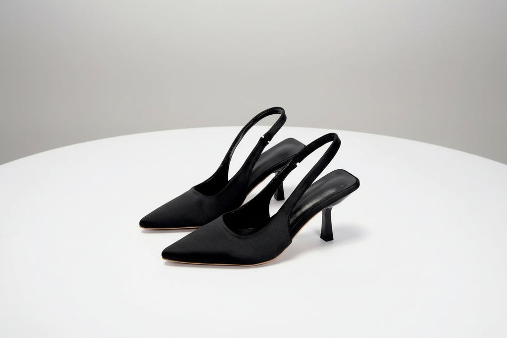 Pair of black high-heeled shoes on a white surface with a light gray background