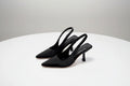 Pair of black high-heeled shoes on a white surface with a light gray background