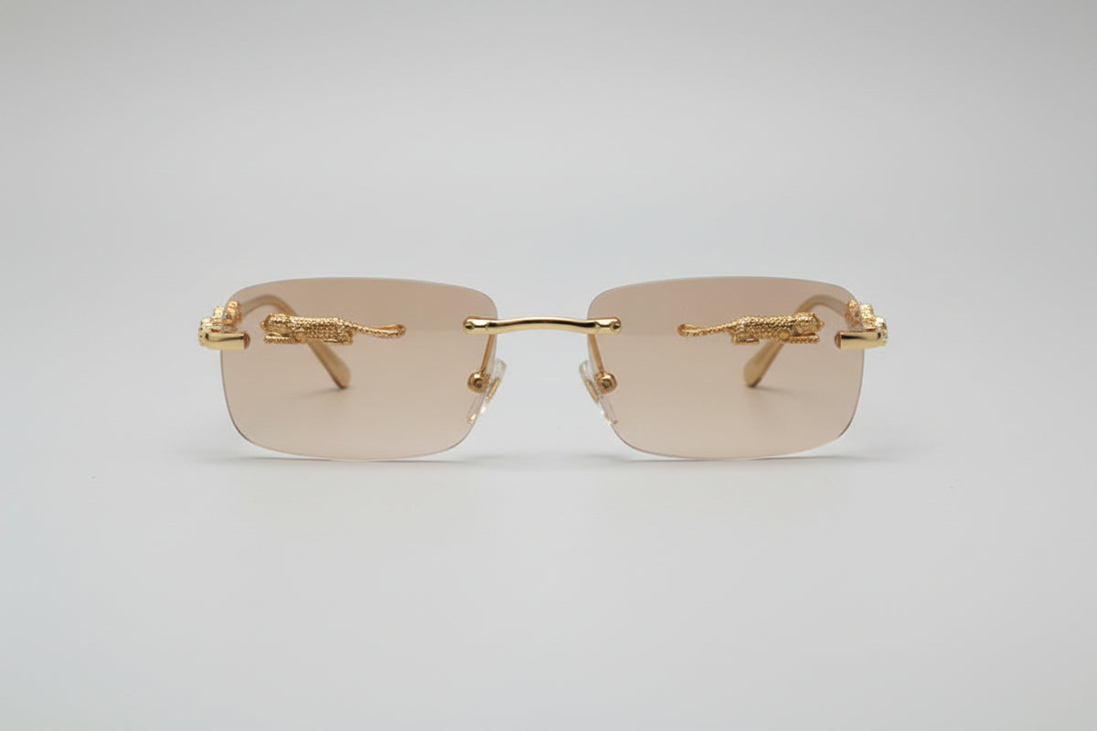Gold-framed sunglasses with beige lenses on a light gray background